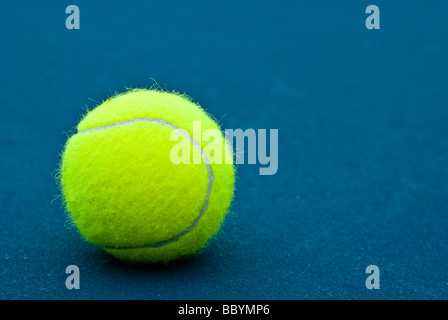 Yellow Tennis Ball on dark blue tennis court Stock Photo