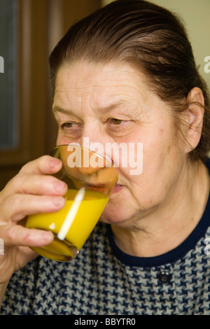 Woman, 67 years old, drinking orange juice Stock Photo