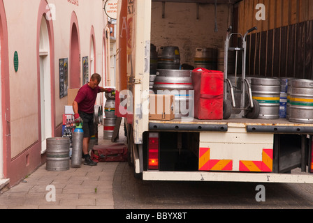 A male man worker unloading beer barrels from the back of a lorry in a uk street Stock Photo