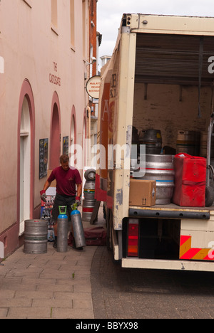 A male man worker unloading beer barrels from the back of a lorry in a uk street Stock Photo