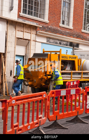 Workmen wearing hard hats at work in a uk street which is closed with barriers due to the roadworks Stock Photo