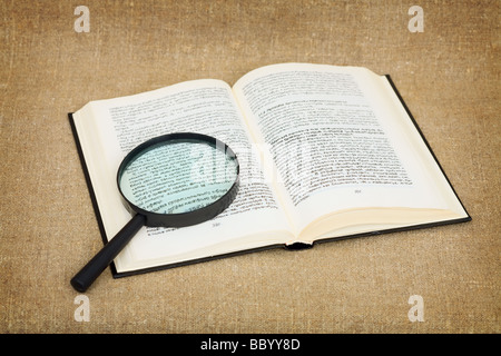 Open book and magnifier on canvas background - a still-life Stock Photo ...