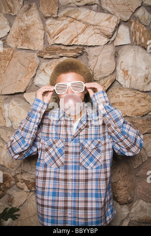 Mixed race boy in sunglasses chewing bubble gum