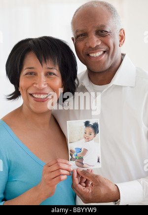 African couple holding photo of granddaughter Stock Photo