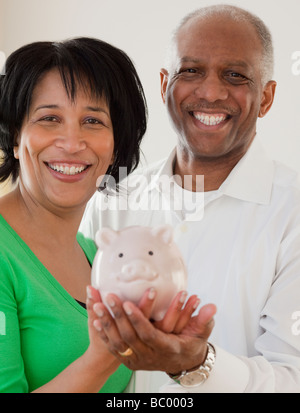 African man looking at a piggy bank through a magnifying glass Stock ...