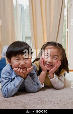 Korean boy and girl laying on the floor smiling Stock Photo
