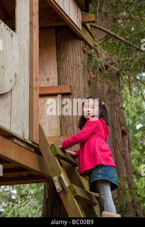 Korean girl climbing into tree house Stock Photo