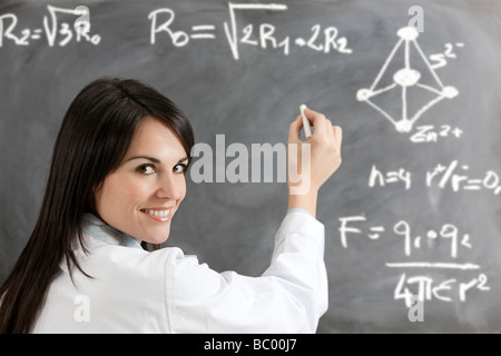 female teacher formulas writing on blackboard Stock Photo