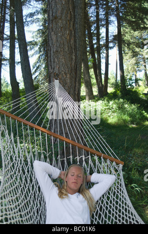 blond woman lying in hammock and reading a book Stock Photo - Alamy