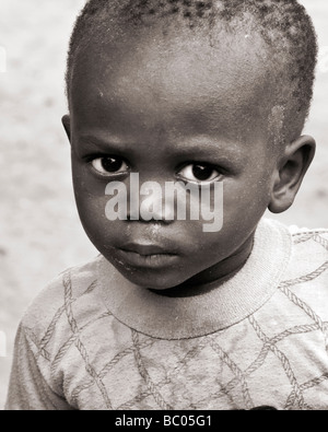 Sepia toned head and shoulders candid portrait of a small black African boy