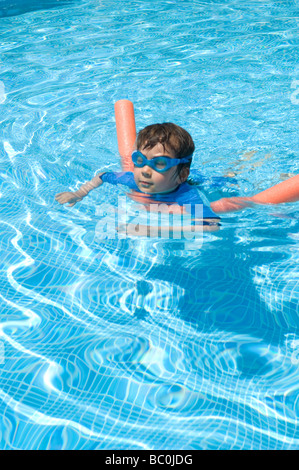 Boy aged 6 swims with the aid of a woggle or noodle in a pool in Majorca, Spain Stock Photo