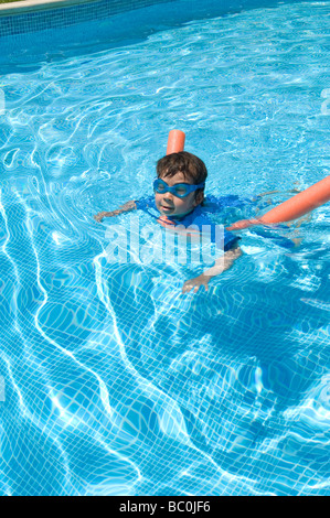 Boy aged 6 swims with the aid of a woggle or noodle in a pool in Majorca, Spain Stock Photo