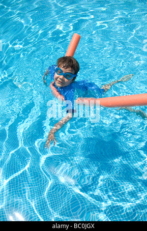 Boy aged 6 swims with the aid of a woggle or noodle in a pool in Majorca, Spain Stock Photo