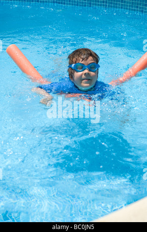 Boy aged 6 swims with the aid of a woggle or noodle in a pool in Majorca, Spain Stock Photo