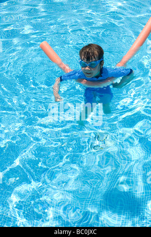 Boy aged 6 swims with the aid of a woggle or noodle in a pool in Majorca, Spain Stock Photo