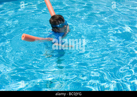 Boy aged 6 swims with the aid of a woggle or noodle in a pool in Majorca, Spain Stock Photo