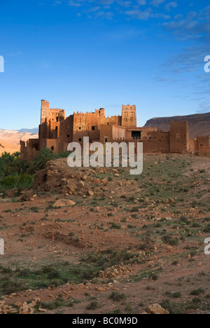 Kasbah Ellouze perched on a rocky outcrop overlooking the date palms and distant Atlas mountains Morocco North Africa Stock Photo
