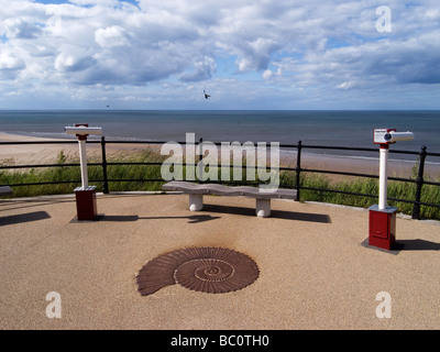 Two seaside telescopes on the promenade at Saltburn by the Sea with a cast iron replica of an ammonite fossil Stock Photo