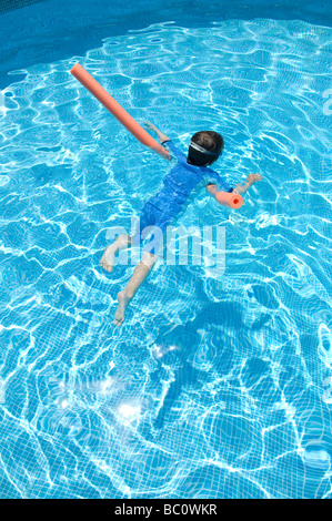 Boy aged 6 swims with the aid of a woggle or noodle in a pool in Majorca, Spain Stock Photo