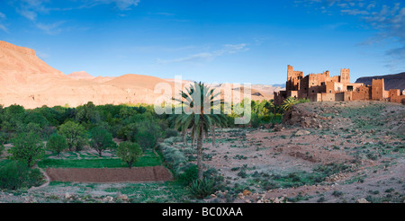 Kasbah Ellouze perched on a rocky outcrop overlooking the date palms and distant Atlas mountains Morocco North Africa Stock Photo