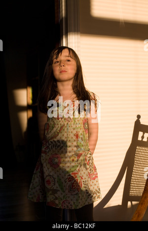 Nine year old girl stands in doorway in early evening light Stock Photo