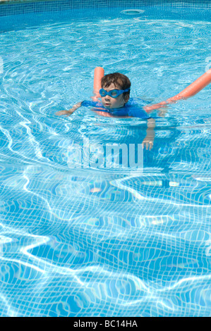 Boy aged 6 swims with the aid of a woggle or noodle in a pool in Majorca, Spain Stock Photo