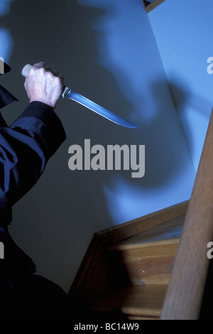 Man with knife and shadow on stairs at a crime scene, USA Stock Photo