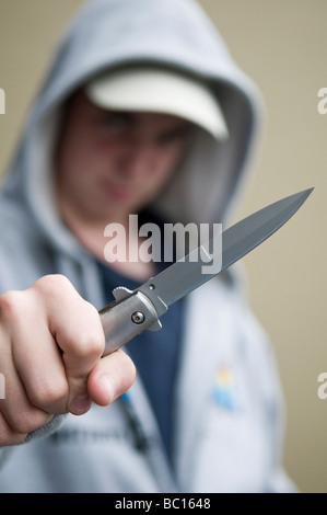 Youth in hoody brandishing flick knife Stock Photo