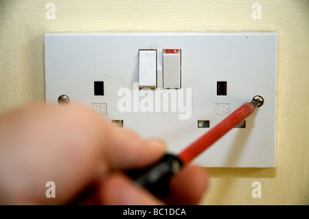 DIY Electrician about to remove a socket cover. Stock Photo