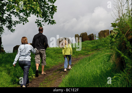 A family taking a walk near Wycoller village in England along a country lane alone a sheep farm marked by standing stones Stock Photo