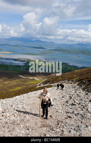 A woman with a walking stick climbing Croagh Patrick in County Mayo Ireland Stock Photo
