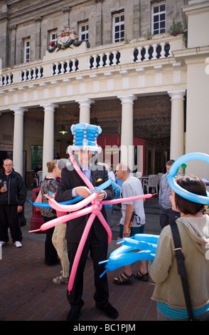 Street entertainer making shapes out of balloons for kids. Chichester, UK Stock Photo
