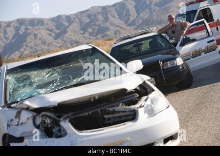 Police officer arrives at scene of carcrash Stock Photo