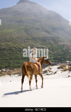 Mid-adult woman riding horse on beach Stock Photo