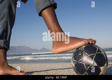 Foot on soccer ball, beach scene Stock Photo