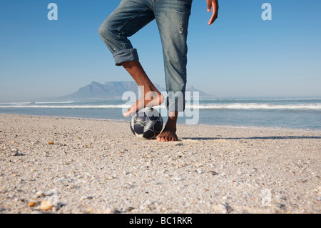 Mans foot on soccer ball, beach scene Stock Photo