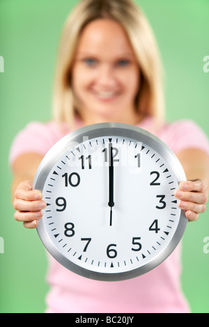 Woman Holding Clock Showing 12 O'Clock Stock Photo