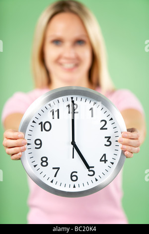 Woman Holding Clock Showing 5 O'Clock Stock Photo