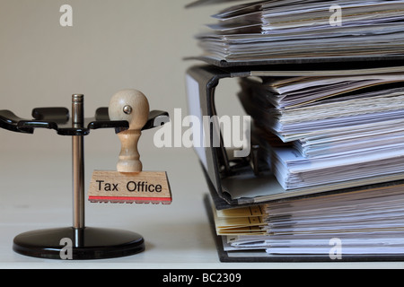 Stamp with inscription Tax Office next to a pile of files