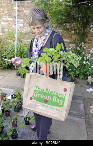 Elegant lady with The Natural Green Bag and carrying plants in garden Stock Photo