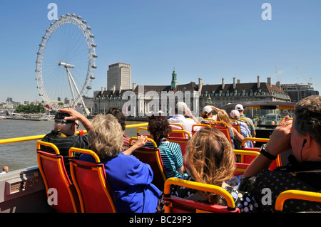 Top deck open top double decker sightseeing tour bus tourist passengers taking pictures River Thames & London Eye from Westminster Bridge England UK Stock Photo