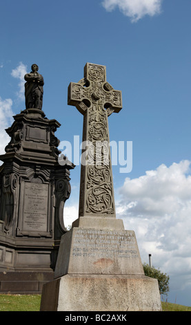 A stone Celtic Cross from 1926 next to a formal memorial dated 1834 in Glasgow's Victorian Necropolis. Stock Photo