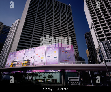 Yellow double-decker bus passing large billboards at an overpass in Hong Kong, China. Stock Photo