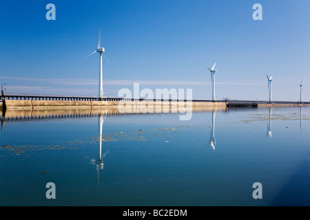 A modern power generating windmill in Blyth in northern England. The windmills on the East Pier reflect in the river Blyth. Stock Photo