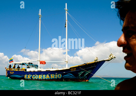 Tourist is disproportionately sized against touristy sail boat on the Caribbean Island of Cubagua in Venezuela. Stock Photo