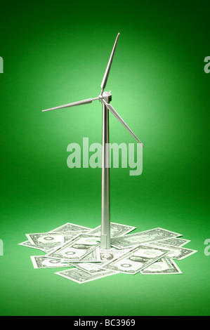 A small metal wind turbine on a green background dollar bills money Stock Photo