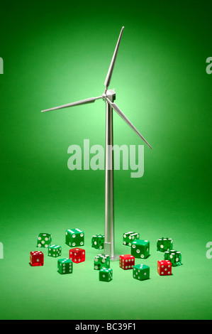 A small metal wind turbine on a green background with dice Stock Photo