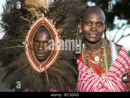 Maasai man traditional ostrich feather headdress married woman bead necklaces earrings Masai Mara National Reserve Kenya Africa Stock Photo