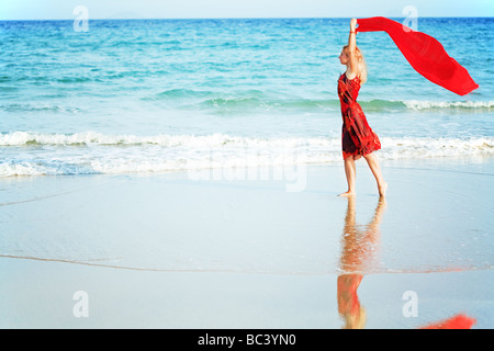 Beautiful woman walking near the ocean with red sarong Stock Photo