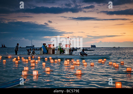 Floating Lanterns drift in the water as a boat with Buddhist monks officiate over the event Stock Photo